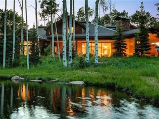 Luxury mountain home nestled amongst aspen trees, offering stunning views and a serene pond.