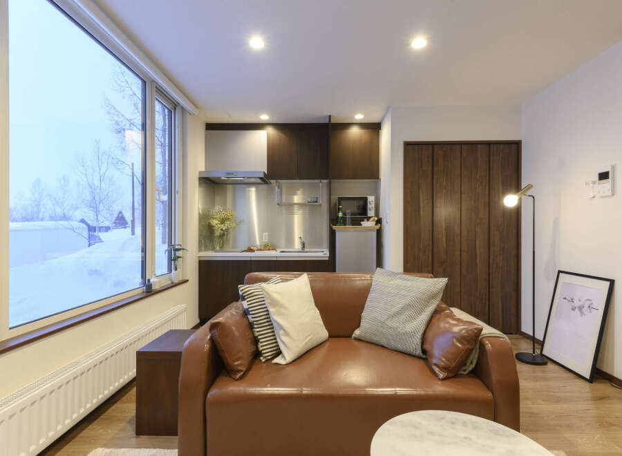 Cozy apartment with snow view, featuring a modern kitchen and comfortable leather sofa.