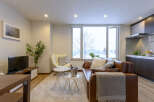 Cozy living room with a brown leather sofa, a large window overlooking a snowy landscape, and modern decor.
