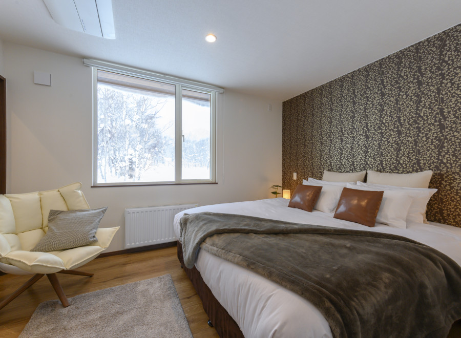 Cozy bedroom with a king-size bed, plush throw, and large window overlooking a snowy landscape.