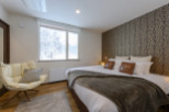Cozy bedroom with a king-size bed, plush throw, and large window overlooking a snowy landscape.