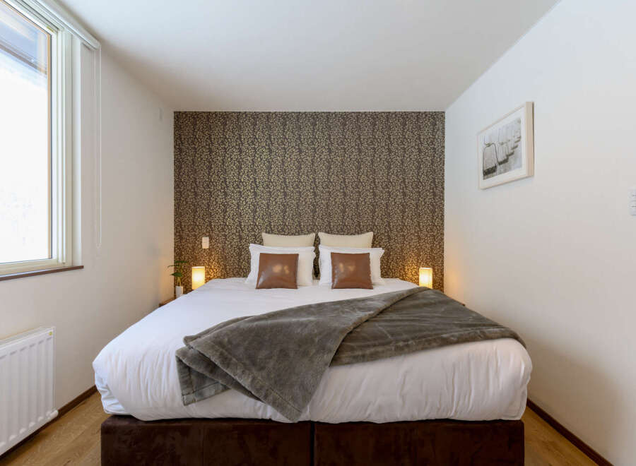 Cozy bedroom with a king-size bed, plush bedding, and a stylish patterned wall.