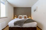 Cozy bedroom with a king-size bed, plush bedding, and a stylish patterned wall.
