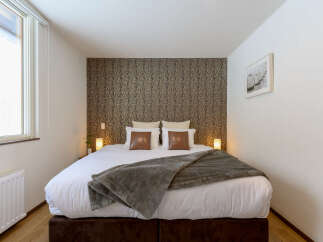 Cozy bedroom with a king-size bed, plush bedding, and a stylish patterned wall.