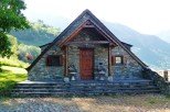 Mountainside stone house with a charming wooden porch and steps.