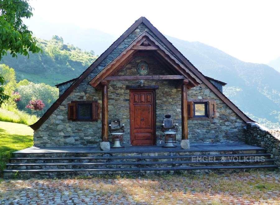 Mountainside stone house with a charming wooden porch and steps.