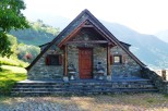 Mountainside stone house with a charming wooden porch and steps.