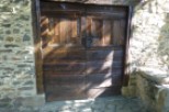 This charming property features rustic wooden doors, adding character and warmth to the stone facade.