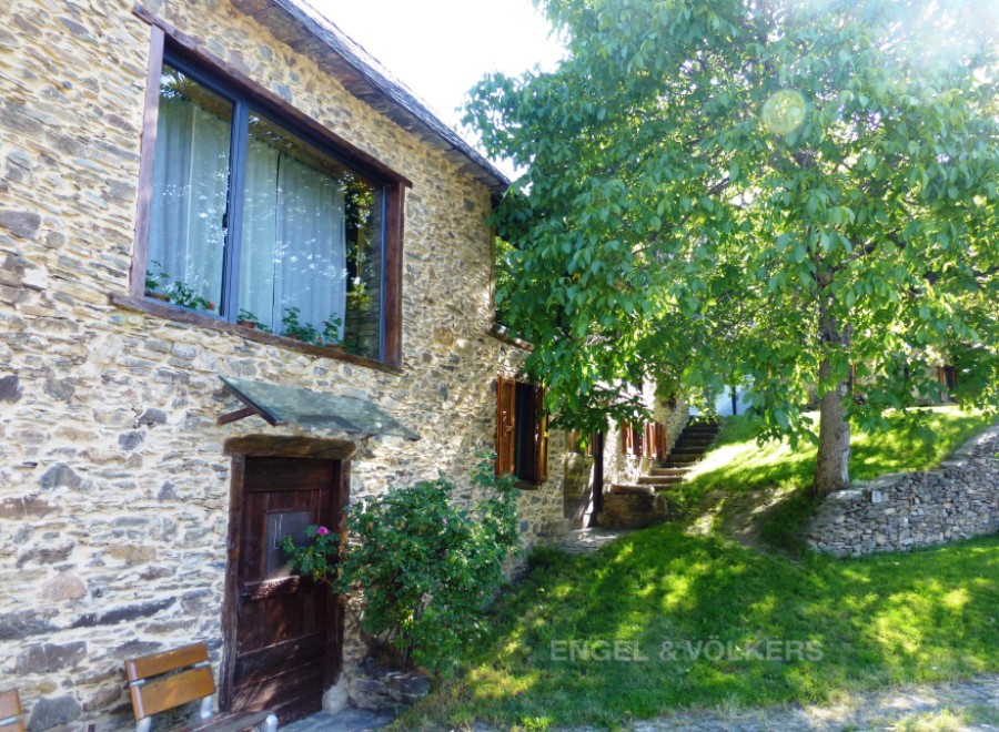 This charming stone house boasts a picturesque setting with a lush green lawn and mature trees.