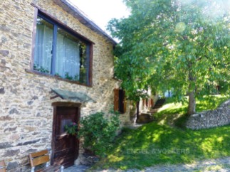 This charming stone house boasts a picturesque setting with a lush green lawn and mature trees.