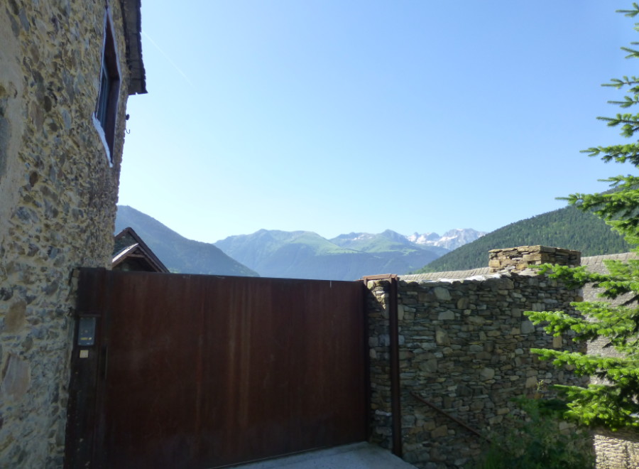Mountain view property with rustic stone walls and a modern metal gate.