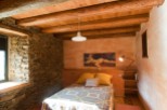 Rustic bedroom with exposed wooden beams and stone walls.