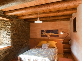 Rustic bedroom with exposed wooden beams and stone walls.