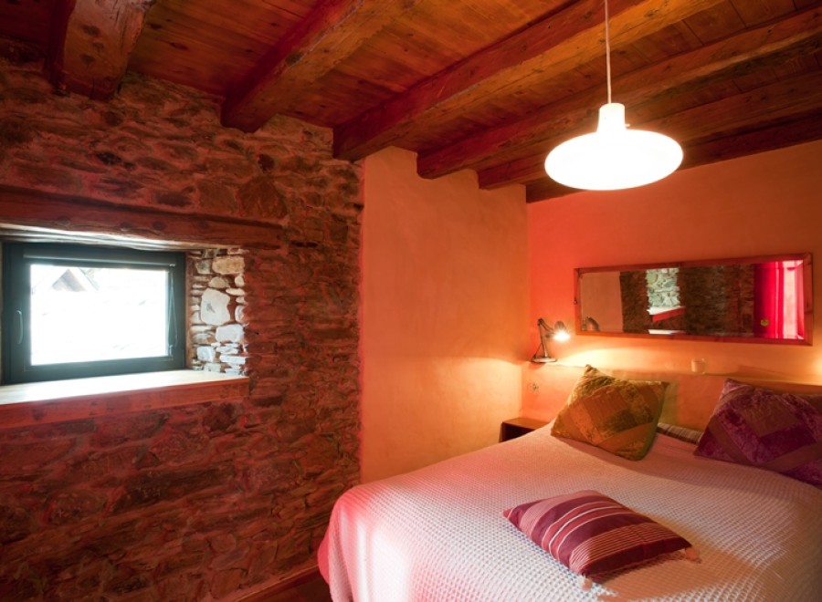 Cozy bedroom with exposed wooden beams and stone walls.
