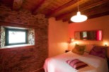 Cozy bedroom with exposed wooden beams and stone walls.