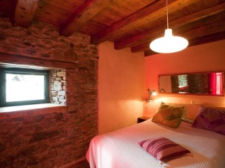 Cozy bedroom with exposed wooden beams and stone walls.