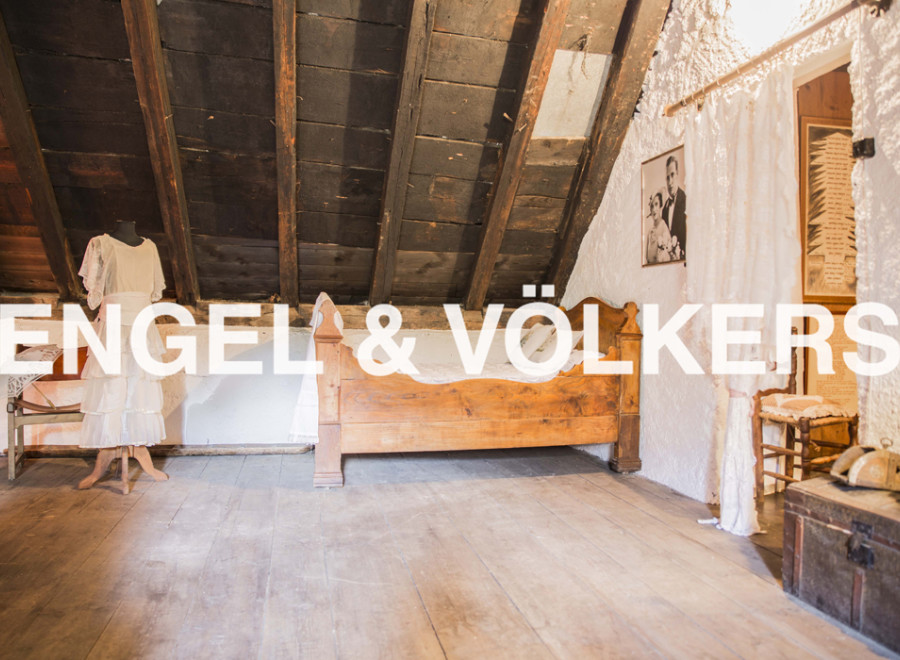 Discover this unique attic room featuring exposed wooden beams, hardwood floors, and antique furnishings.