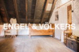 Discover this unique attic room featuring exposed wooden beams, hardwood floors, and antique furnishings.