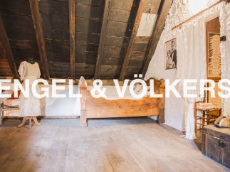 Discover this unique attic room featuring exposed wooden beams, hardwood floors, and antique furnishings.