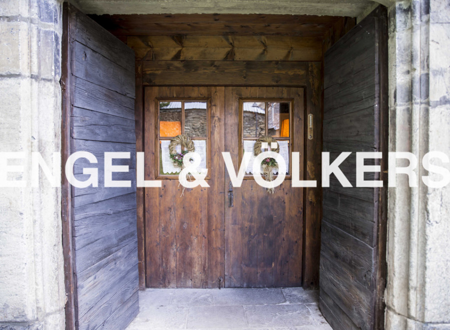 Charming rustic doorway with double wooden doors, showcasing intricate details and welcoming wreaths.