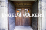 Charming rustic doorway with double wooden doors, showcasing intricate details and welcoming wreaths.