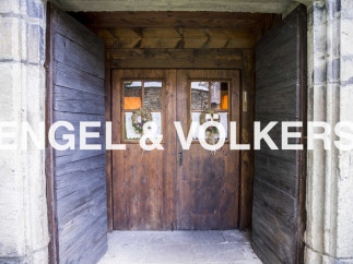 Charming rustic doorway with double wooden doors, showcasing intricate details and welcoming wreaths.