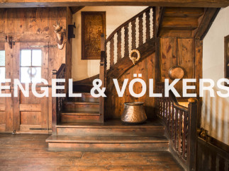 This stunning property boasts a grand wooden staircase, antique copper cookware, and unique wooden wall paneling.