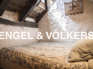 Charming attic bedroom with exposed wooden beams and whitewashed walls.