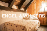 Cozy attic bedroom with exposed wooden beams and charming floral quilt.