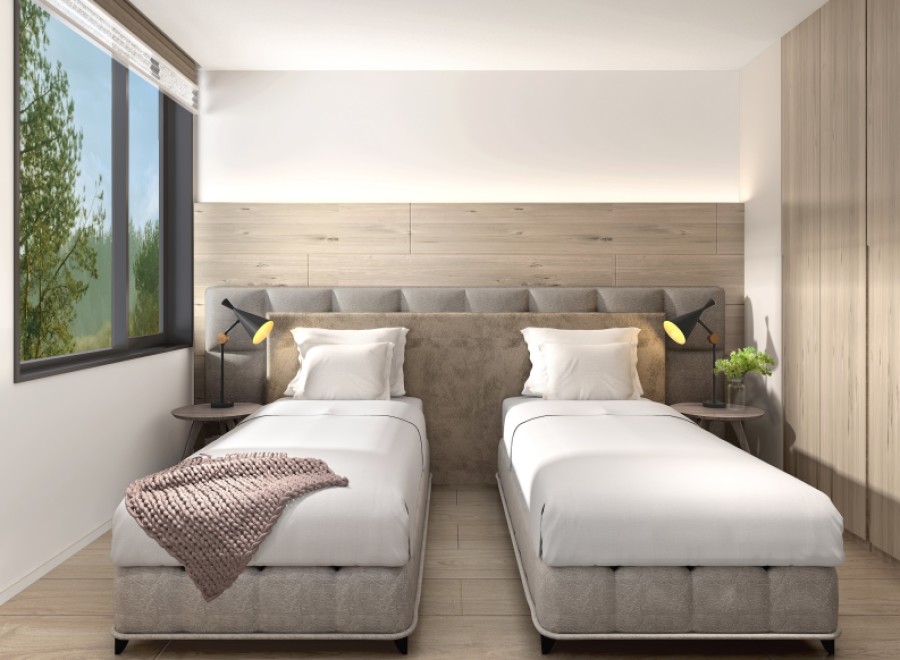This serene bedroom boasts twin beds with plush gray upholstery, complemented by a light wood wall and floor.