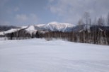 A stunning winter landscape unfolds, showcasing a snow-covered mountain range under a cloudy sky.