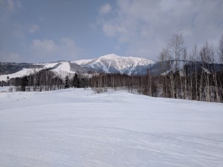 A stunning winter landscape unfolds, showcasing a snow-covered mountain range under a cloudy sky.