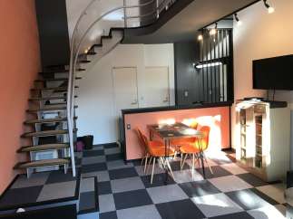 This modern apartment boasts a unique spiral staircase and stylish orange accents.
