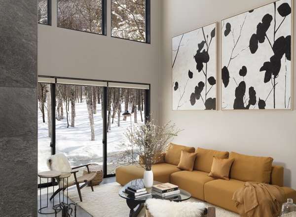 This stunning modern home boasts a spacious open-plan living area with floor-to-ceiling windows offering breathtaking views of a snow-covered landscape.