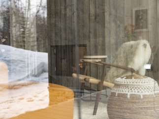 Cozy cabin living room with a fireplace, wooden chair, and sheepskin throw.