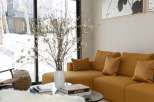 This stunning living room boasts a spacious sectional sofa in a rich mustard yellow, complemented by plush throw pillows.