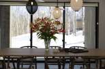 Modern dining room with large windows showcasing snowy landscape.