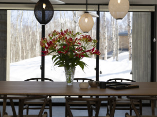 Modern dining room with large windows showcasing snowy landscape.