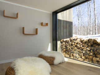 Cozy living space featuring floor seating with fluffy sheepskin throws and woven baskets, complemented by minimalist wooden shelves on a neutral wall.