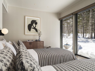 This stunning bedroom boasts a cozy and sophisticated atmosphere, featuring a chic monochrome color scheme and a comfortable bed with patterned bedding.