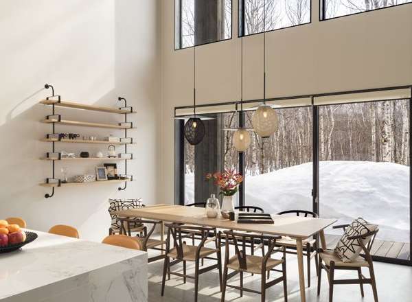 This stunning home boasts a spacious open-plan living area with floor-to-ceiling windows offering breathtaking views of a snowy landscape.