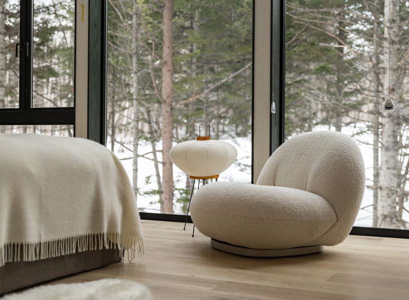 Cozy bedroom with floor-to-ceiling windows showcasing a snowy forest view.