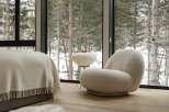 Cozy bedroom with floor-to-ceiling windows showcasing a snowy forest view.