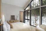 Wake up to breathtaking views of a snow-covered forest from this luxurious bedroom.