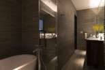 This luxurious bathroom boasts a sleek, modern design with dark brown tile, a frameless glass shower enclosure, and a freestanding soaking tub.