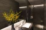 Luxurious bathroom with dark gray tile, modern sink and fixtures, and yellow orchids adding a touch of elegance.