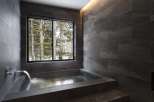 Indulge in tranquility with this stunning bathroom featuring a built-in soaking tub and a large window showcasing breathtaking views of a snow-covered forest.