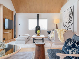This stunning living room boasts a vaulted wood ceiling, large windows offering abundant natural light, and a cozy fireplace as a focal point.
