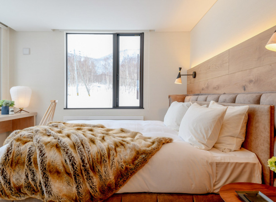 This luxurious bedroom boasts a king-size bed with plush bedding and a cozy faux fur throw, perfect for relaxing after a day on the slopes.