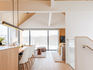 This stunning property boasts an open-concept living area with floor-to-ceiling windows offering breathtaking views of a snow-covered landscape.